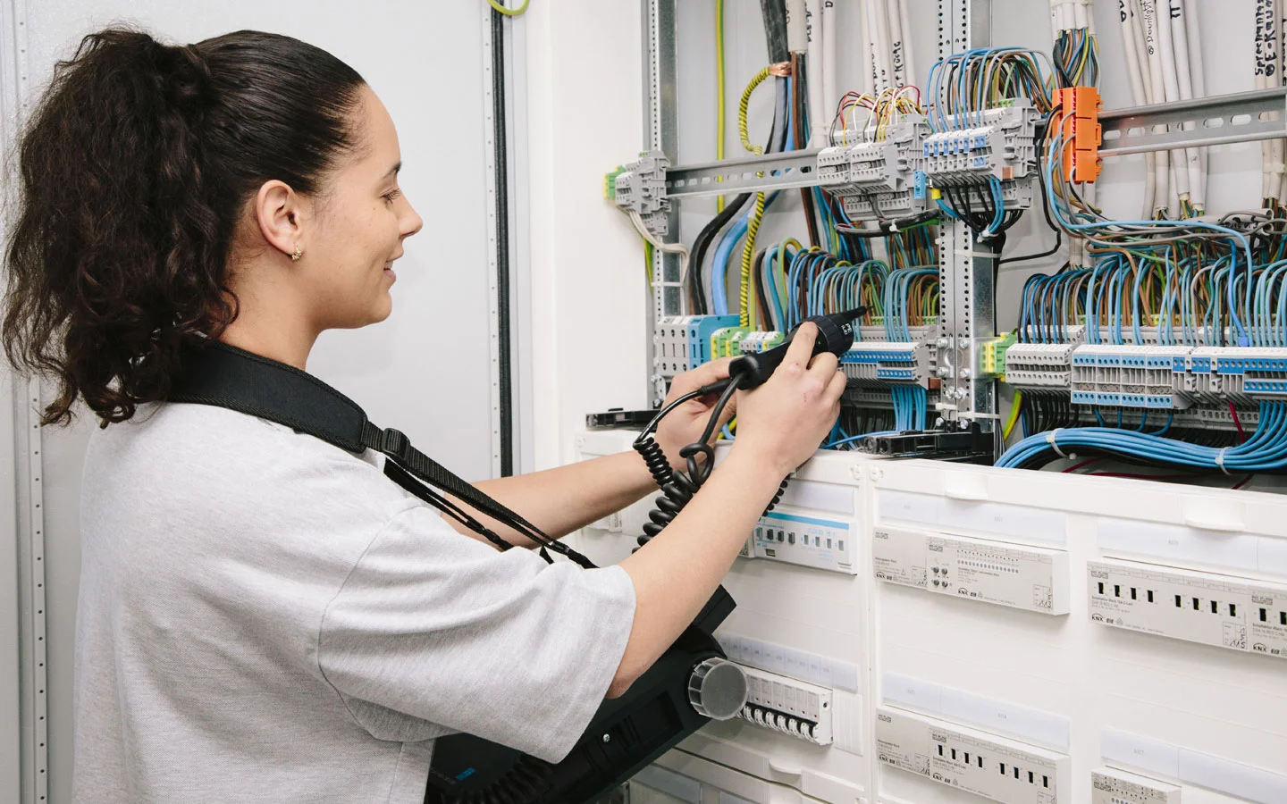 E-CHECK - Mitarbeiterin prüft im Schaltschrank mit einem Meßgerät &middot; Elektro-Adam-Mühlheim